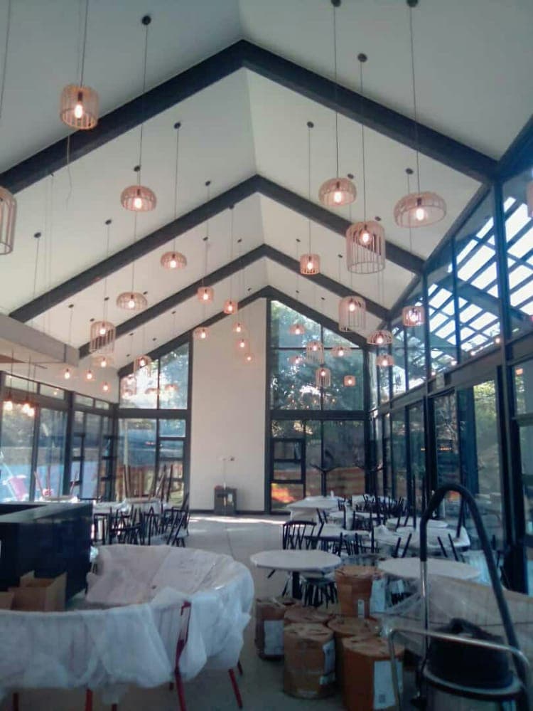 Rows of copper cage pendant lights hanging from a vaulted steel-beam ceiling in a commercial space