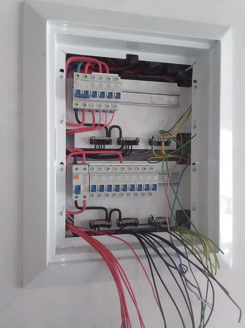Open residential distribution board with circuit breakers and coloured wiring during an upgrade